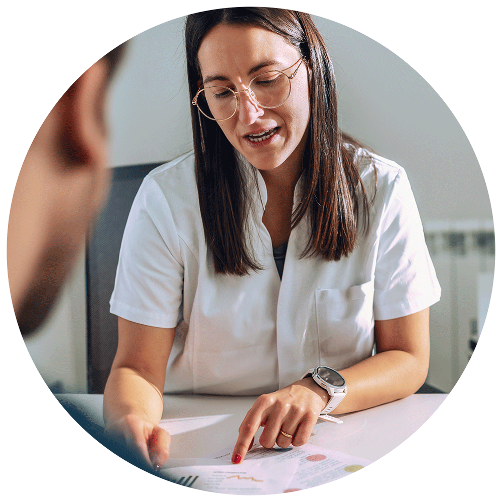 Nutritionist in white coat sits with patient pointing at charts.