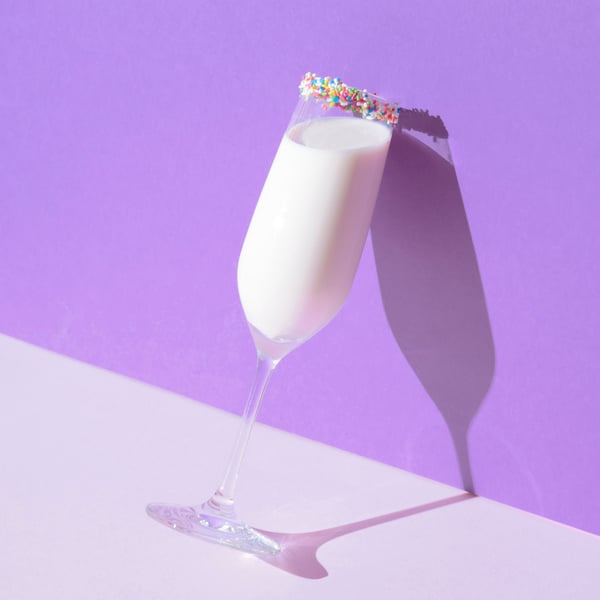 Martini glass with sprinkle room leaning against a wall holding white protein milk